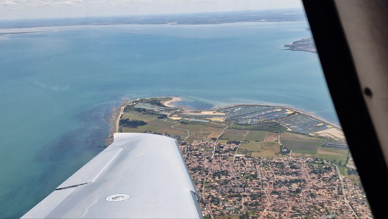 Aircraft wing on approach over a European coastline